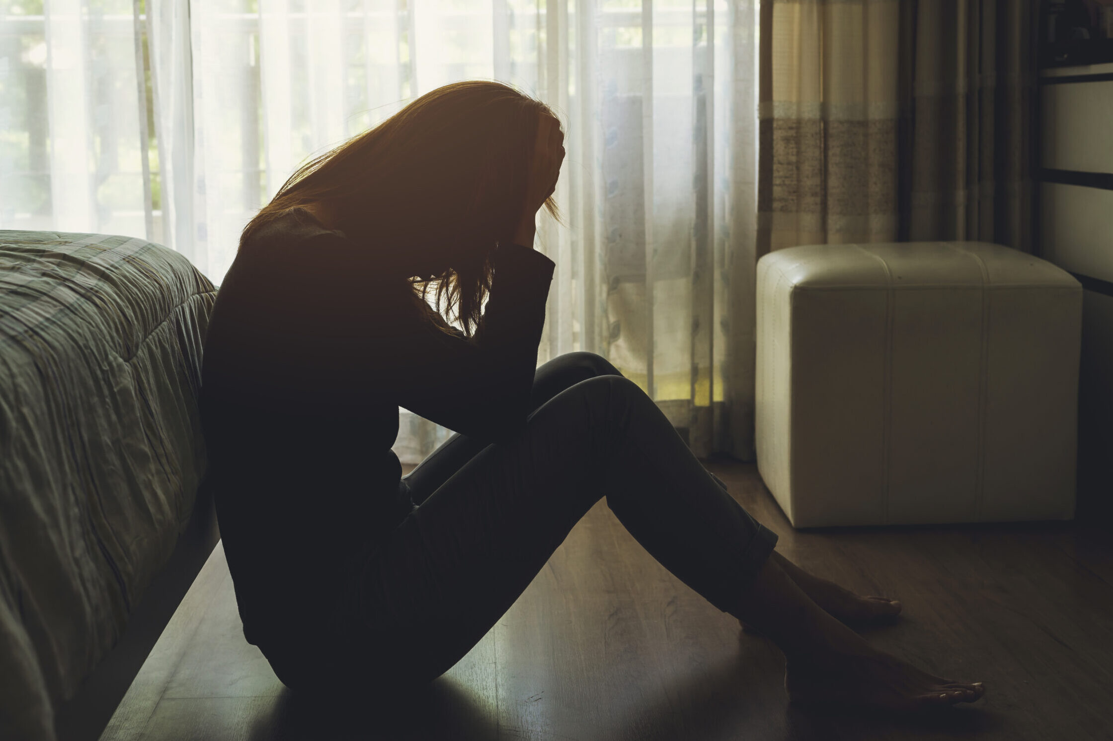 depressed woman sitting in the dark bedroom